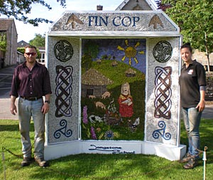 Clive Waddington and Phillipa Cockburn of Archaeological Research Services standing by the Longstone School Well Dressing which portrays events at Fin Cop