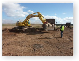 A mechanical digger is used to strip the topsoil from a site before archaeologists begin the excavation