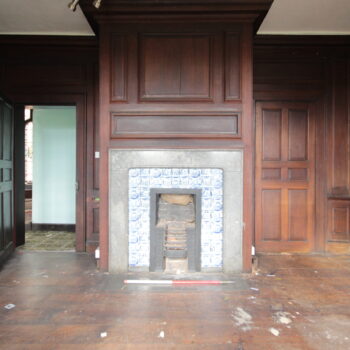 View of the timber panelling and fireplace with austere surround and delft tiling within one of the Hall's main bedrooms © Copyright ARS Ltd 2022